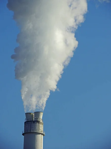 蓝天下一家工厂的工业烟道里冒出的一缕垂直的烟 — 图库照片