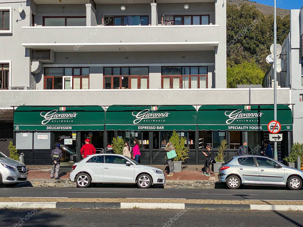 CAPE TOWN, SOUTH AFRICA - May 12, 2020: Customers standing in queue observing social distancing guidelines while waiting to enter Giovanni's deli on a Sunday morning in Cape Town