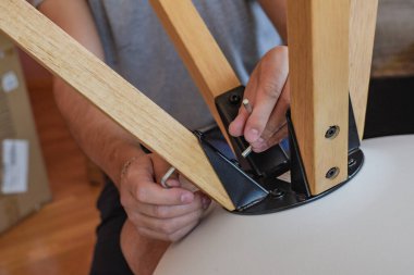 A closeup shot of a handyman assembling a chair clipart