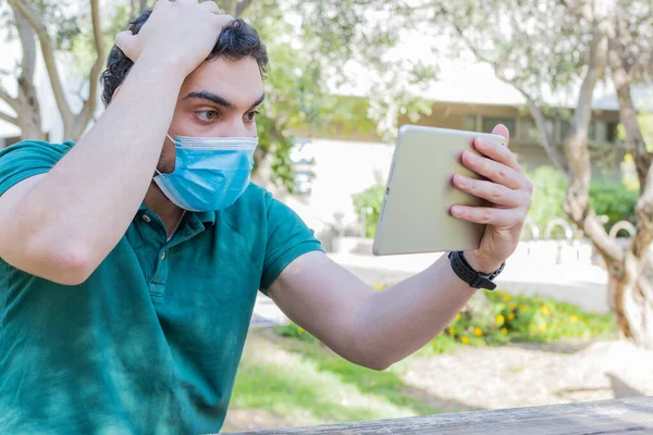 Een Bezorgde Blanke Man Met Een Gezichtsmasker Die Een Tablet — Stockfoto