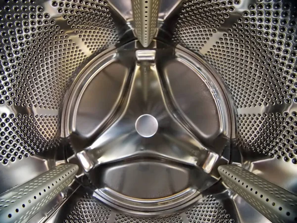 A closeup of a washing machine steel drum under the lights