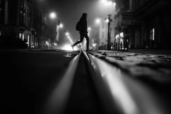 一个人在夜晚穿过街道的灰白色照片 — 图库照片