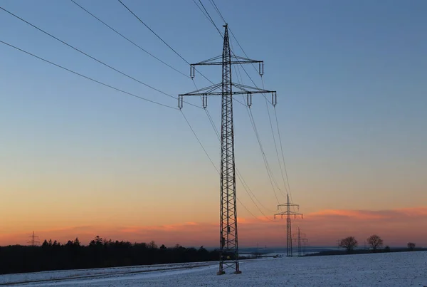 Ett Fält Täckt Snö Omgivet Träd Och Utväxlingstorn Solnedgången — Stockfoto