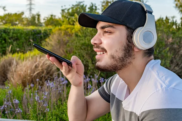 Joven Con Auriculares Gorra Envía Mensaje Voz Mientras Está Sentado —  Fotos de Stock