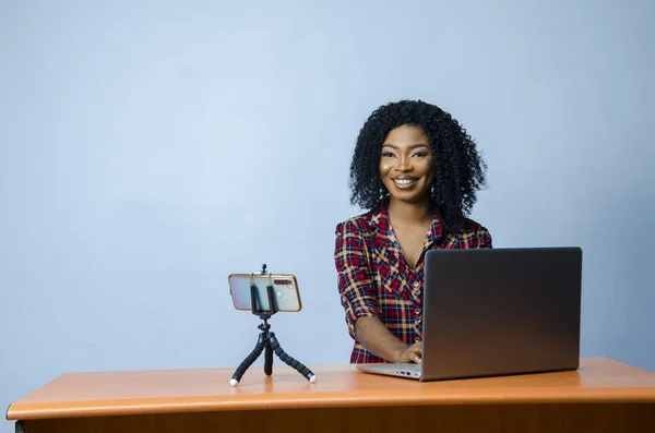 在一张特写照片中 一位年轻的尼日利亚女士在一个带着笔记本电脑和手机的视频电话中坐在桌子上 — 图库照片