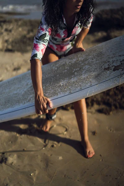 海にサーフボードを持っている女性の垂直ショット — ストック写真
