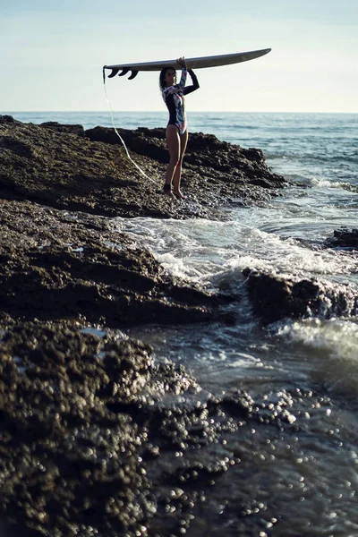 一只雌性带着冲浪板向海洋的垂直拍 — 图库照片