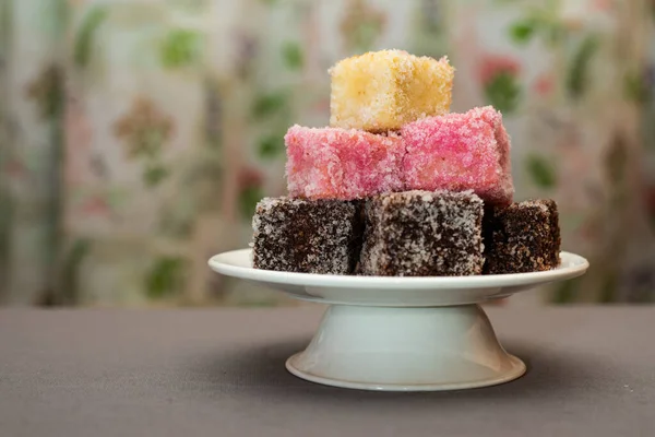 一张澳大利亚色彩斑斓的甜点拉明顿的特写镜头堆放在一个蛋糕摊上 — 图库照片