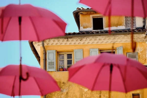 An old building with pink umbrellas on a foreground