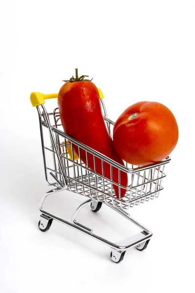 在白色背景的购物车上垂直拍摄的长胡椒和西红柿 — 图库照片