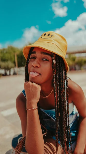 A beautiful female with dreadlocks in a bucket hat posing at camera