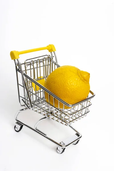 白色底色购物车里一个黄色柠檬的垂直镜头 — 图库照片