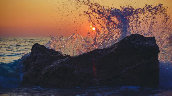 Nahaufnahme Von Meereswellen Die Bei Sonnenuntergang Gegen Die Felsen Schlagen — Stockfoto
