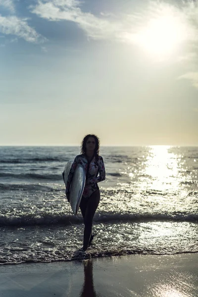 ビーチでサーフィンボードをもたらすヨーロッパの女性の垂直ショット — ストック写真