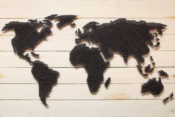 世界上一张用钉子和线在木制表面上绘制的小世界地图的特写 — 图库照片