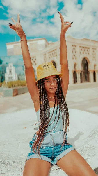A beautiful female with dreadlocks in a bucket hat posing at camera
