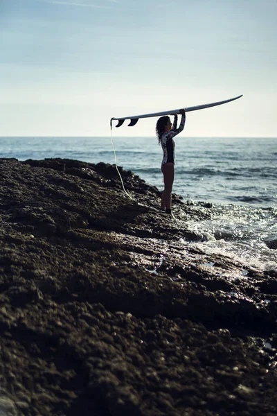 ビーチで楽しいサーフボードを持つ若いサーファーの女性の垂直ショット — ストック写真