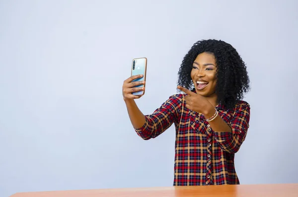 一个快乐的非洲女人拿着一部带着兴奋表情的手机 — 图库照片