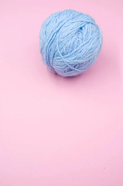 Вертикальный Снимок Шара Голубой Пряжи Розовой Поверхности — стоковое фото