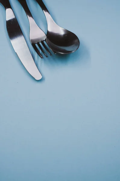 Disparo Vertical Una Cuchara Tenedor Cuchillo Sobre Una Superficie Azul —  Fotos de Stock