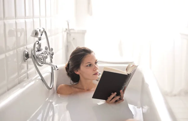Μια Νεαρή Γυναίκα Ξαπλωμένη Μια Μπανιέρα Και Διαβάζοντας Ένα Βιβλίο — Φωτογραφία Αρχείου