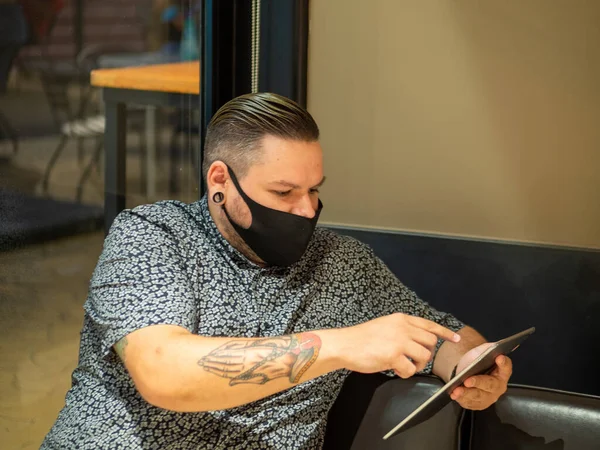 Una Inyección Hombre Con Una Máscara Médica Café Mirando Tableta — Foto de Stock