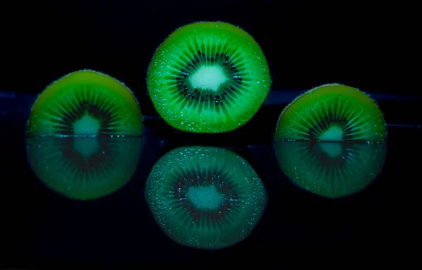 Een Close Shot Van Kiwi Plakjes Water Donkere Achtergrond — Stockfoto