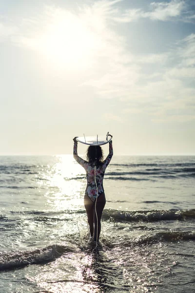 夕阳西下时一个高加索女人冲浪的垂直镜头 — 图库照片