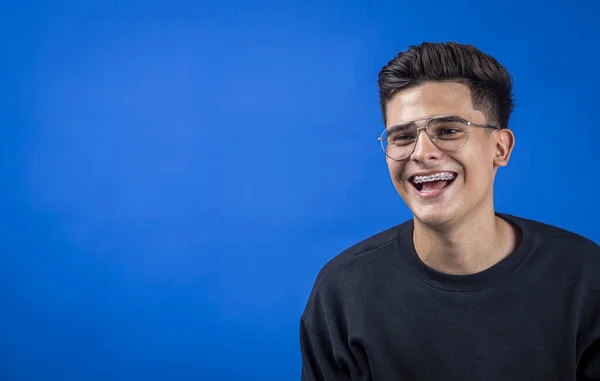 A closeup portrait of a cute young man with aviator glasses and trendy hairstyle smiling happily