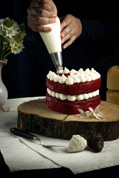 赤いベルベットのケーキに白いクリームを追加する人の垂直ショット — ストック写真