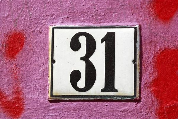 The white house number plate number 31 on a red-painted house wall, Germany, Europe