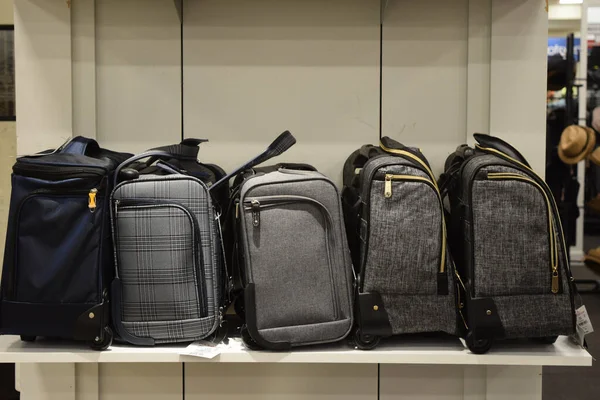 A closeup of small gray suitcases on a shelf at a store with a blurry background