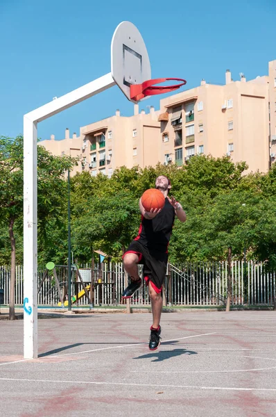 バスケットボールのバスケットにボールを投げ若い男の垂直ショット — ストック写真