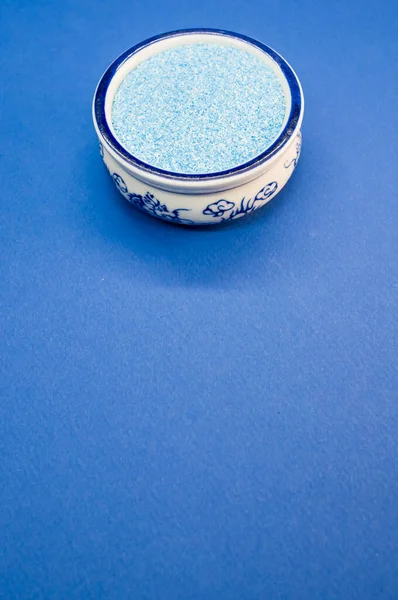 蓝色表面上的中国碗中的蓝色沙粒的垂直射击 — 图库照片