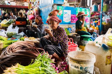 KAMPOT, CAMBODIA - Aug 06, 2019: A woman trader having breakfast while selling vegetables and fruit at the Kampot fresh market clipart