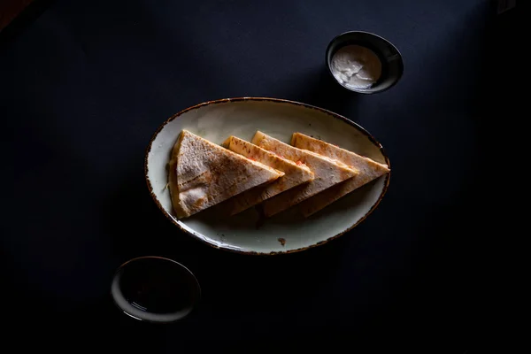 黒の背景に隔離されたソースと食欲をそそるチキンケサディーヤ — ストック写真