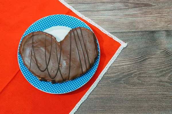 在放在木制表面的盘子上的巧克力包着椒盐卷饼的顶部视图 形状像心脏 — 图库照片