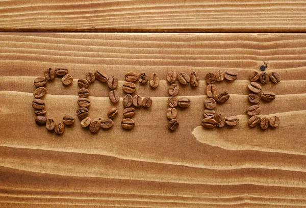 Das Wort Kaffee Geschrieben Von Kaffeebohnen Auf Einer Holzoberfläche — Stockfoto