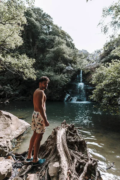 一个年轻的白人男子在岩石附近美丽的瀑布边玩乐 — 图库照片