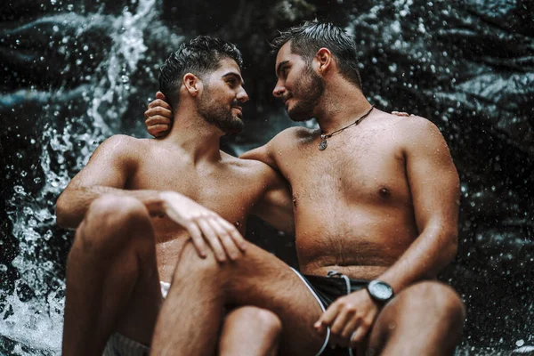 Szczęśliwa Para Gejów Siedzi Skale Pobliżu Pięknego Wodospadu — Zdjęcie stockowe