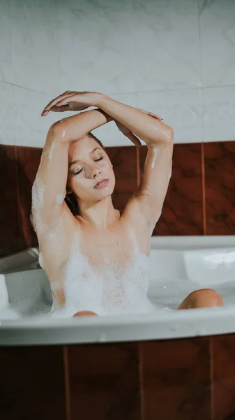 Güzel Genç Bir Kadının Küvette Köpük Banyosunun Keyfini Çıkarırken Dikey — Stok fotoğraf