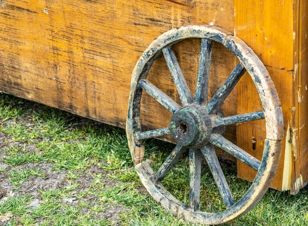 Closeup Shot Old Weathered Wheel Leaning Yellow Wooden Surface — Stock Photo, Image