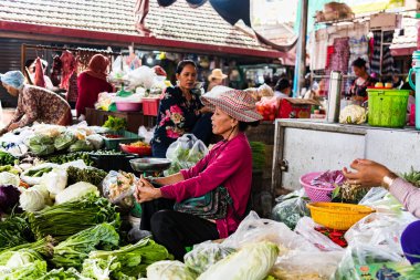 KAMPOT, CAMBODIA - Aug 07, 2019: A woman trader selling vegetables and fruit at the  A woman trader selling vegetables and fruit at the Kampot fresh market clipart