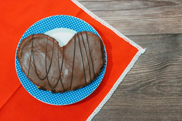 在放在木制表面的盘子上的巧克力包着椒盐卷饼的顶部视图 形状像心脏 — 图库照片