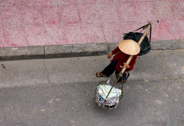 竹篮头顶上一个头戴传统锥形帽子 肩上扛着竹篮的人的照片 — 图库照片