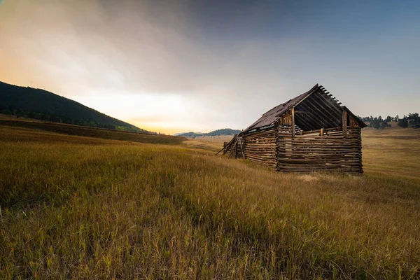 芝生の農場の丘の中腹にある古い木製の納屋の壮大なショット — ストック写真