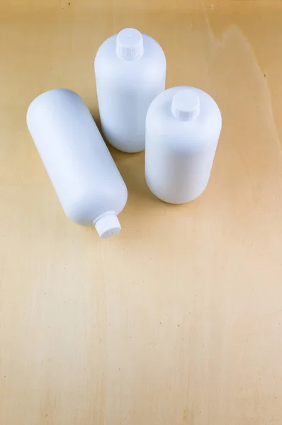 Een Verticaal Shot Van Drie Witte Plastic Flessen Een Lichtbruin — Stockfoto