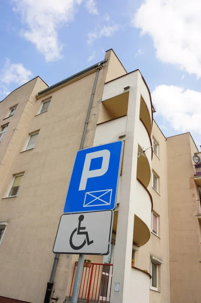 以建筑物为背景图的残疾人蓝色停车标志的垂直截图 — 图库照片