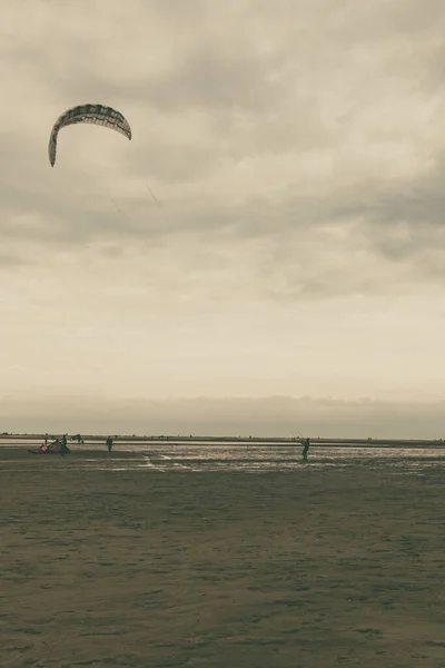 Schöne Aufnahme Eines Sandstrandes Vor Bewölktem Himmel Mit Einem Fallschirmspringer — Stockfoto