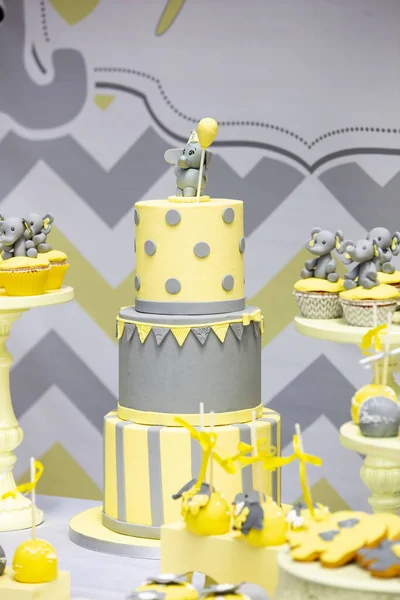 誕生日パーティー中にテーブルの上に象で飾られた3階建てのケーキとカップケーキの垂直ショット — ストック写真